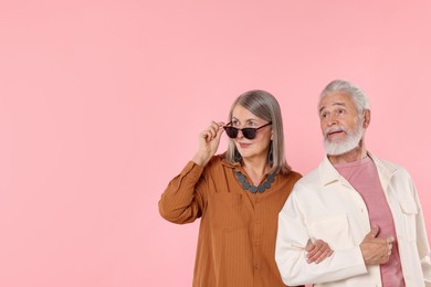 Photo of Senior couple in stylish outfits on pink background, space for text