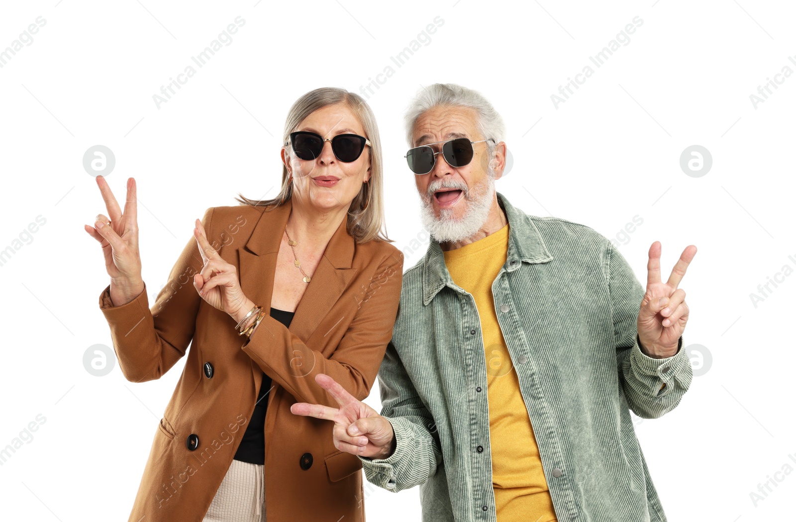 Senior couple in stylish outfits showing V-signs on white background Photo of Senior couple in stylish outfits showing V-signs on white background