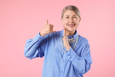 Photo of Senior woman wearing elegant pearl jewelry on pink background