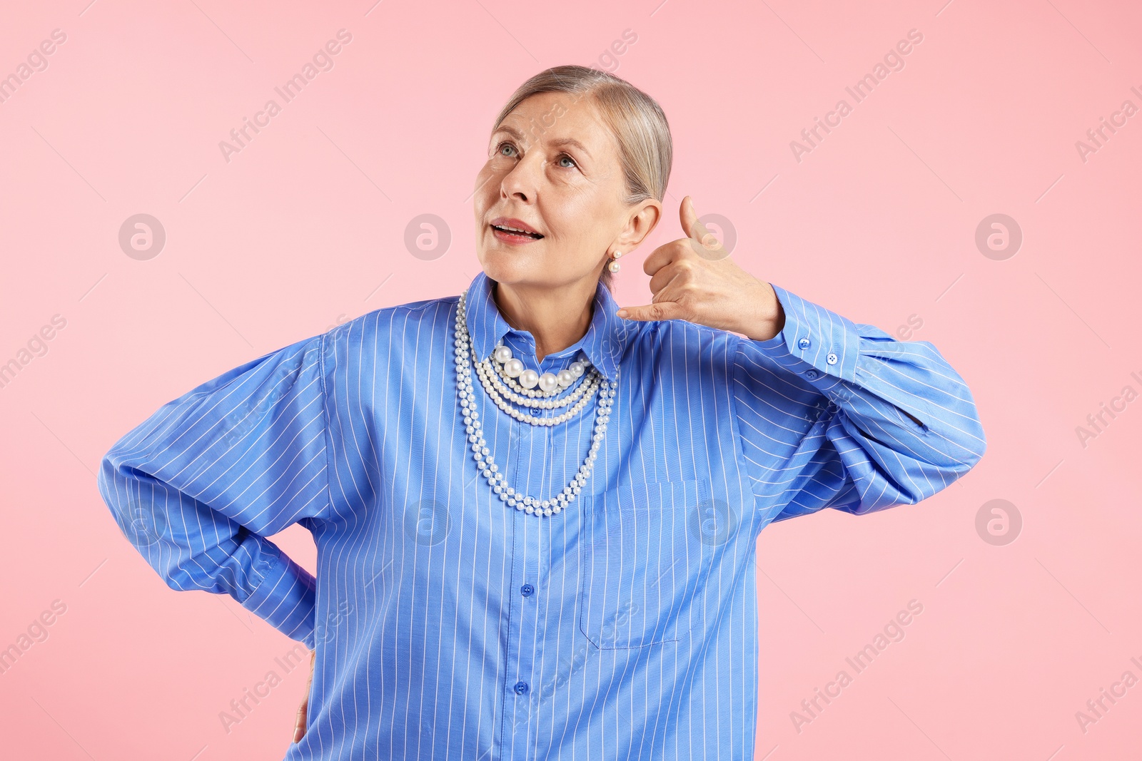 Senior woman wearing elegant pearl jewelry on pink background Photo of Senior woman wearing elegant pearl jewelry on pink background