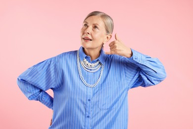 Photo of Senior woman wearing elegant pearl jewelry on pink background