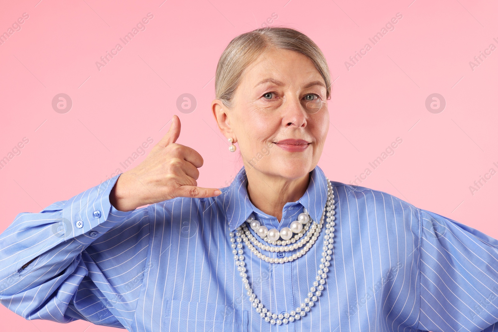 Senior woman wearing elegant pearl jewelry on pink background Photo of Senior woman wearing elegant pearl jewelry on pink background