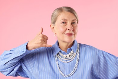 Photo of Senior woman wearing elegant pearl jewelry on pink background