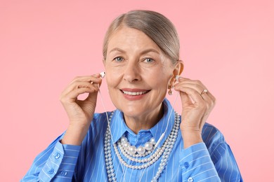 Photo of Senior woman with earphones on pink background