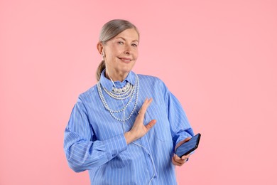 Photo of Senior woman in earphones listening to music on pink background