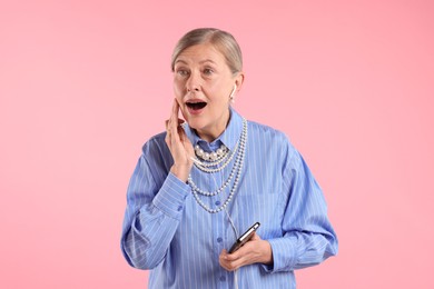 Photo of Senior woman in earphones listening to music on pink background