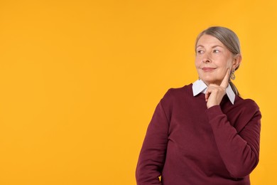 Photo of Happy senior woman in stylish outfit on orange background, space for text