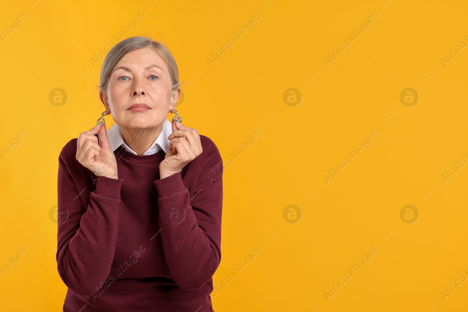 Happy senior woman in stylish outfit on orange background, space for text Photo of Happy senior woman in stylish outfit on orange background, space for text