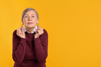 Photo of Happy senior woman in stylish outfit on orange background, space for text