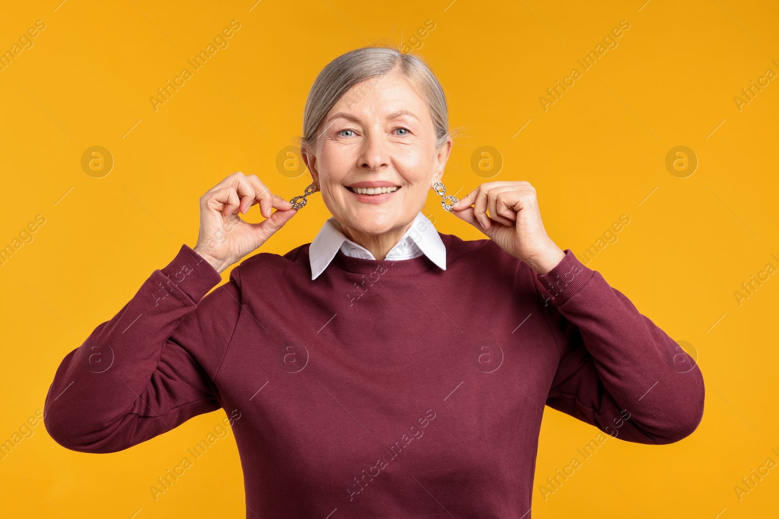 Happy senior woman in stylish outfit on orange background Photo of Happy senior woman in stylish outfit on orange background