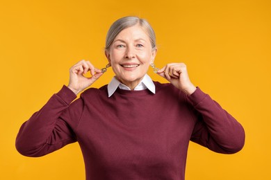 Photo of Happy senior woman in stylish outfit on orange background