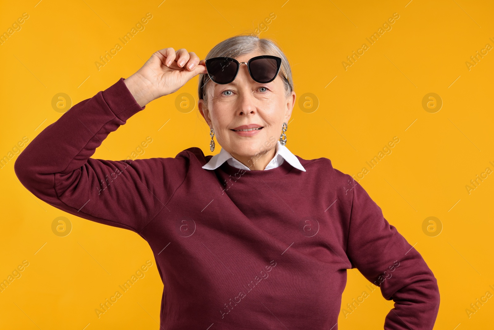 Happy senior woman in stylish outfit on orange background Photo of Happy senior woman in stylish outfit on orange background