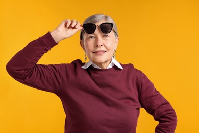 Photo of Happy senior woman in stylish outfit on orange background
