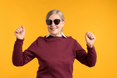 Photo of Happy senior woman in stylish outfit on orange background
