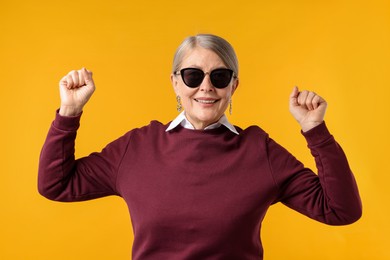 Photo of Happy senior woman in stylish outfit on orange background