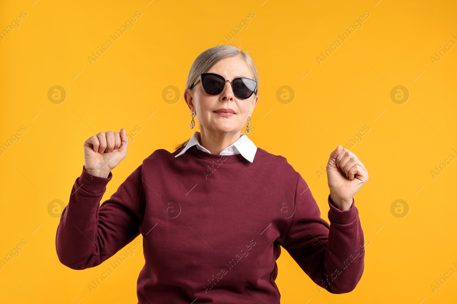 Happy senior woman in stylish outfit on orange background Photo of Happy senior woman in stylish outfit on orange background