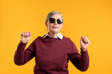 Photo of Happy senior woman in stylish outfit on orange background