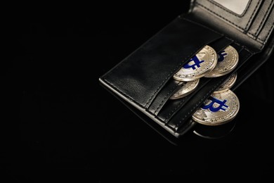 Photo of Cryptocurrency. Bitcoins in wallet on black mirror surface, above view. Space for text
