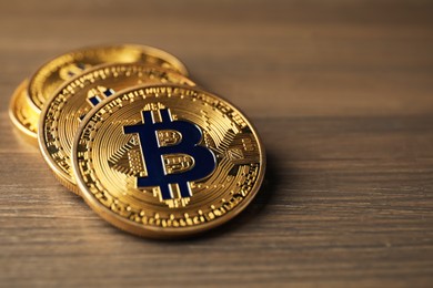 Photo of Cryptocurrency. Many bitcoins on wooden table, closeup. Space for text