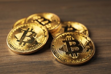 Photo of Cryptocurrency. Many bitcoins on wooden table, closeup