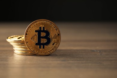Photo of Cryptocurrency. Many bitcoins on wooden table, closeup. Space for text