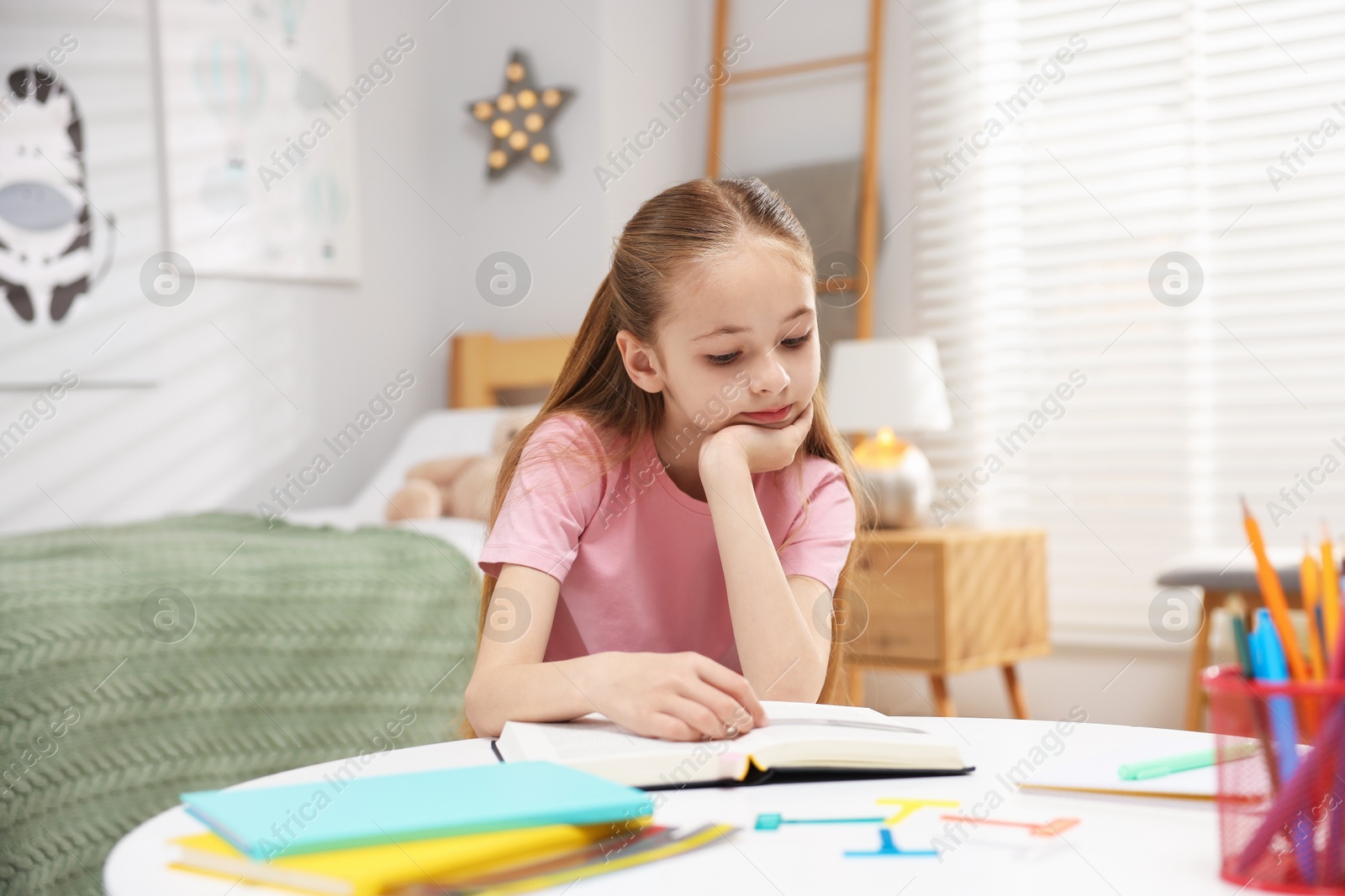 Dyslexia. Upset little girl reading book at table indoors Photo of Dyslexia. Upset little girl reading book at table indoors