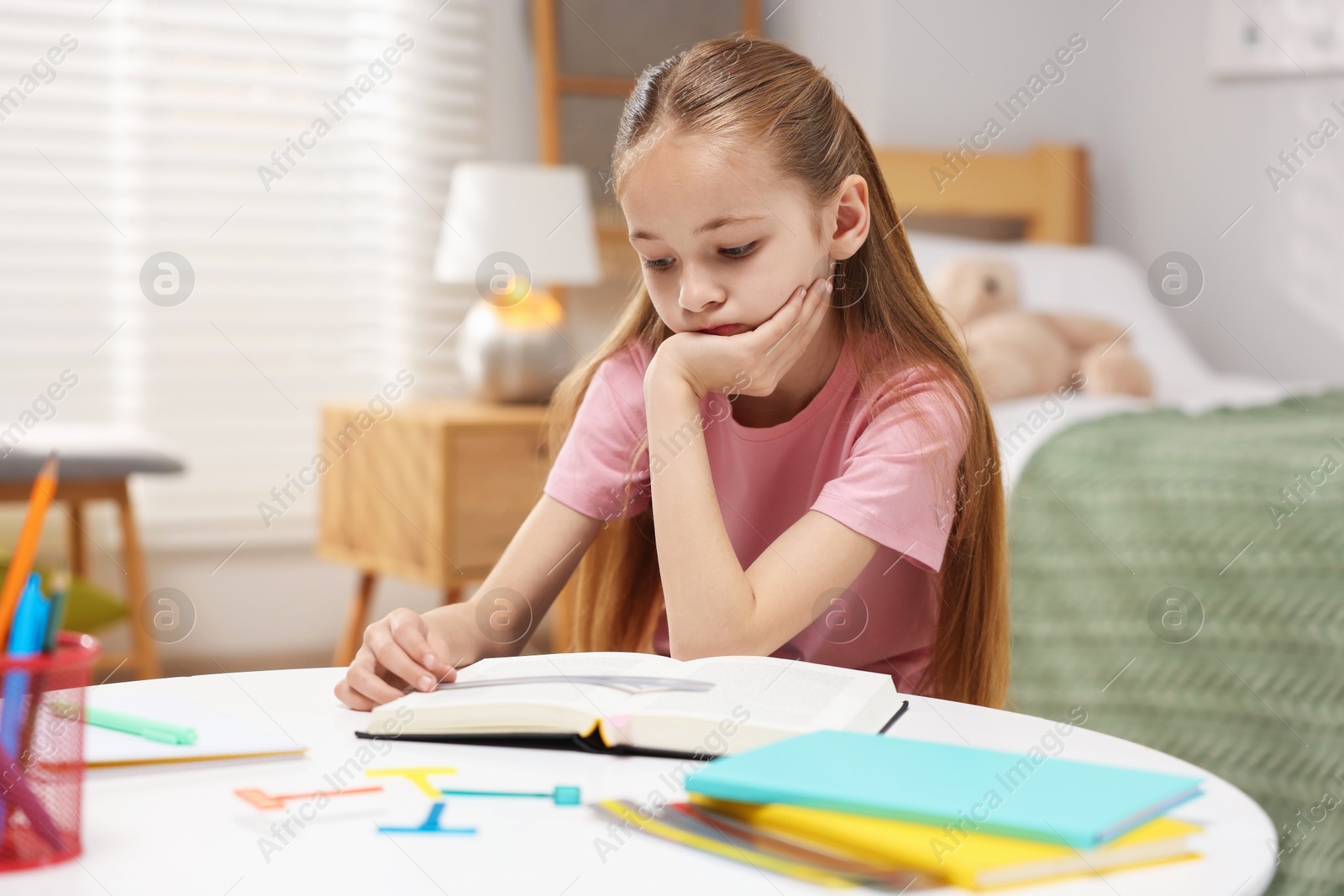 Dyslexia. Upset little girl reading book at table indoors Photo of Dyslexia. Upset little girl reading book at table indoors
