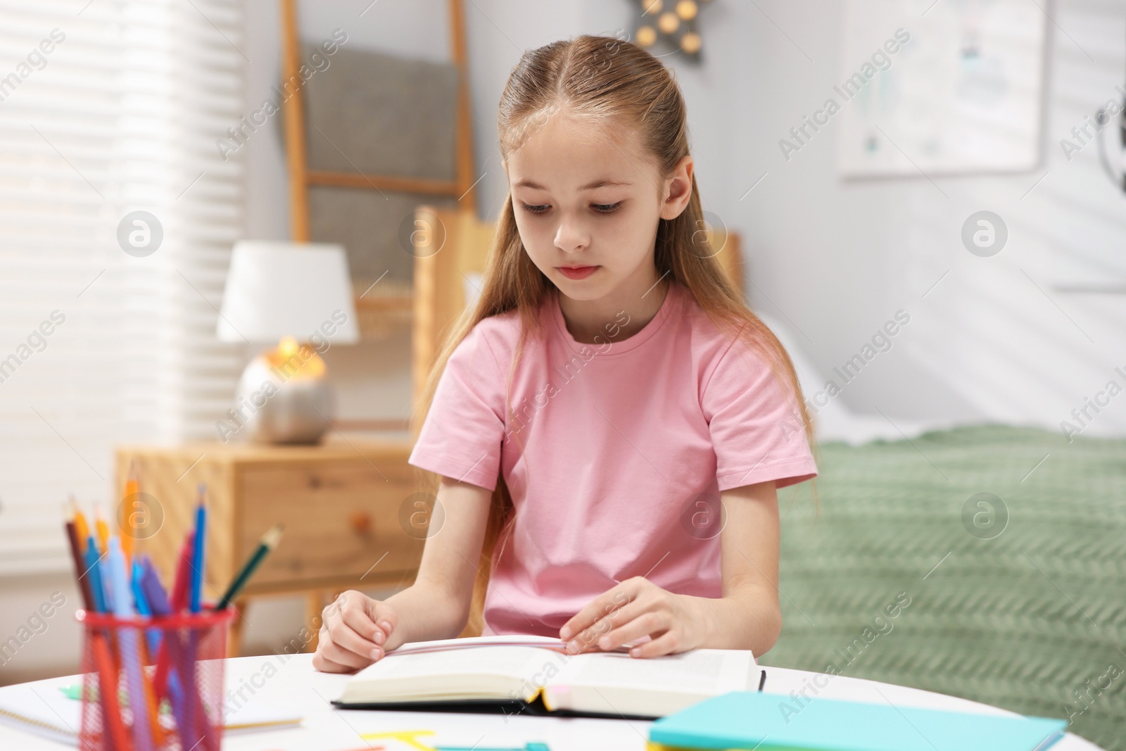 Dyslexia. Little girl reading book at table indoors Photo of Dyslexia. Little girl reading book at table indoors