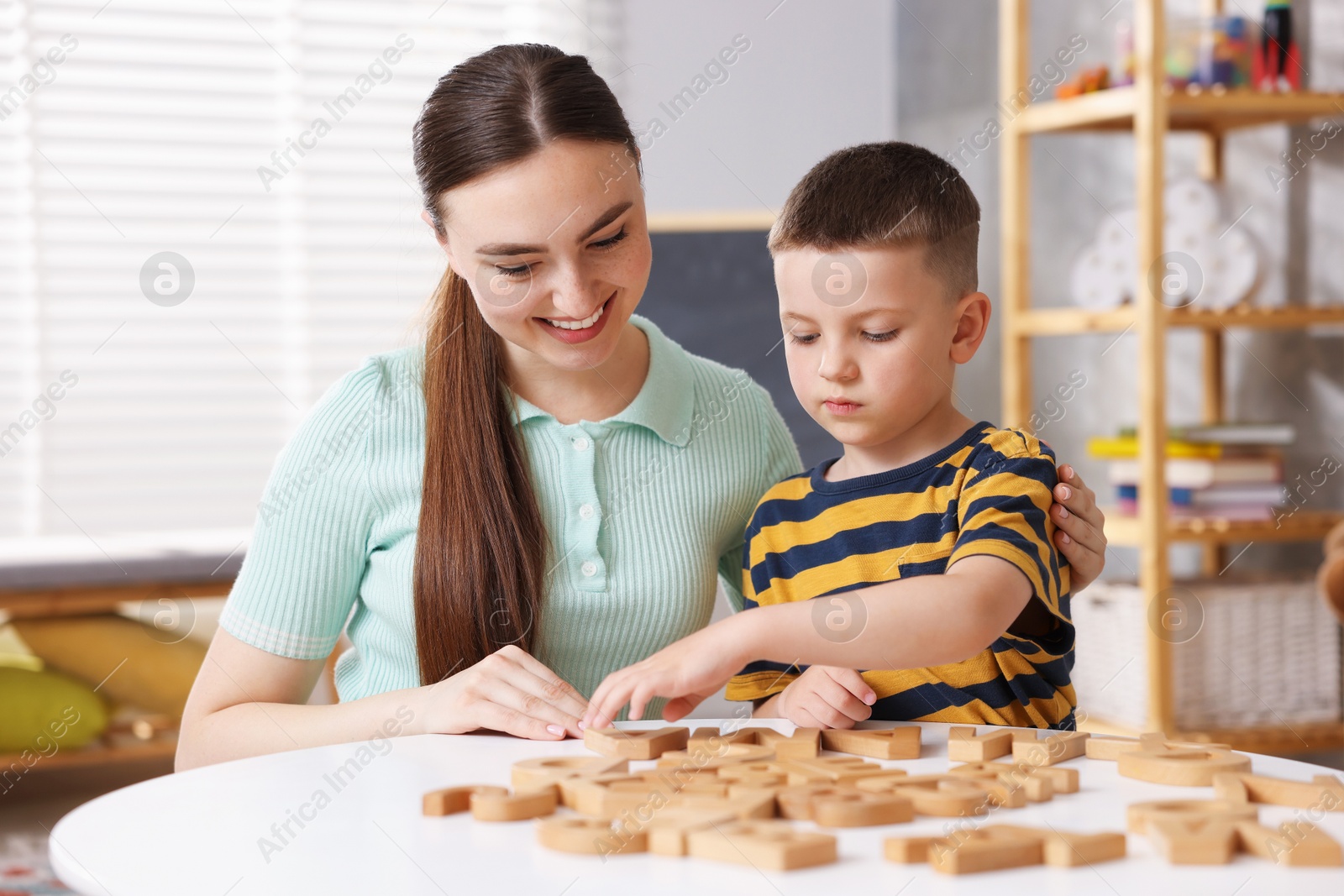 Dyslexia. Mother and her son learning letters at table indoors Photo of Dyslexia. Mother and her son learning letters at table indoors