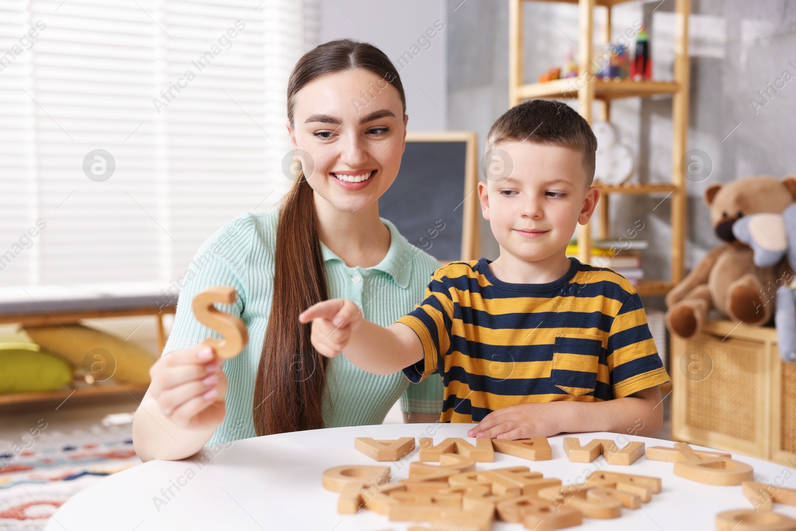 Dyslexia. Mother and her son learning letters at table indoors Photo of Dyslexia. Mother and her son learning letters at table indoors
