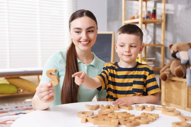 Photo of Dyslexia. Mother and her son learning letters at table indoors