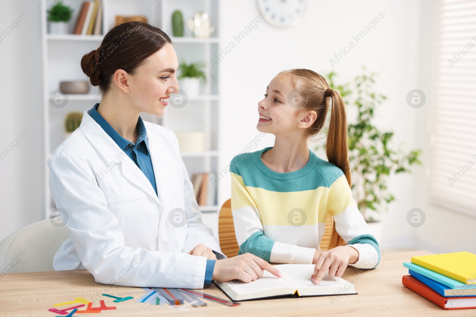 Dyslexia treatment. Pediatrician working with little girl at table indoors Photo of Dyslexia treatment. Pediatrician working with little girl at table indoors