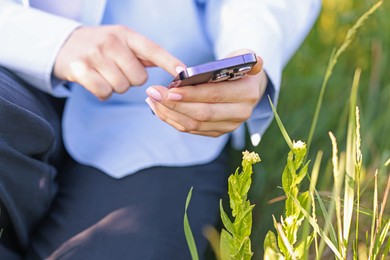 Photo of Woman using plant recognition application on smartphone outdoors, closeup