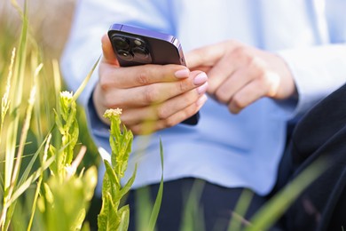 Photo of Woman using plant recognition application on smartphone outdoors, closeup