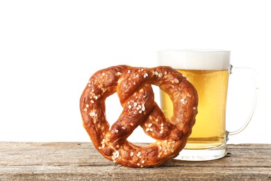 Photo of Tasty pretzel and glass of beer on wooden table against white background. Space for text