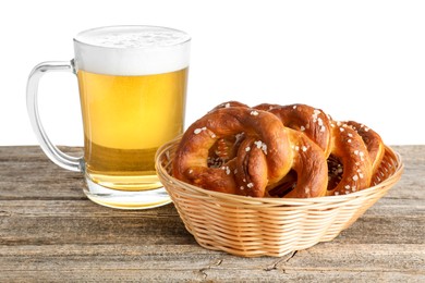 Photo of Tasty pretzels and glass of beer on wooden table against white background