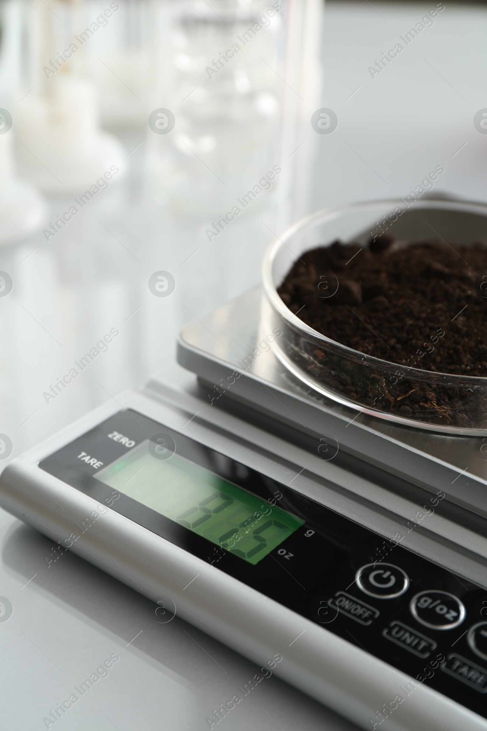 Scale with Petri dish of sample on white mirror table, closeup Photo of Scale with Petri dish of sample on white mirror table, closeup