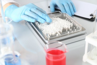 Photo of Scientist weighing sample on scales at white mirror table, closeup