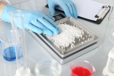 Photo of Scientist weighing sample on scales at white mirror table, closeup