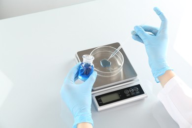 Photo of Scientist working with samples and scales at white mirror table in laboratory, closeup