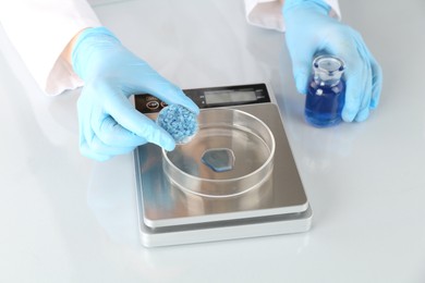 Photo of Scientist working with samples and scales at white mirror table in laboratory, closeup