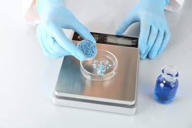 Photo of Scientist weighing sample on scales at white mirror table, closeup