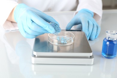 Photo of Scientist weighing sample on scales at white mirror table, closeup
