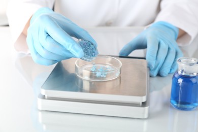 Photo of Scientist weighing sample on scales at white mirror table, closeup