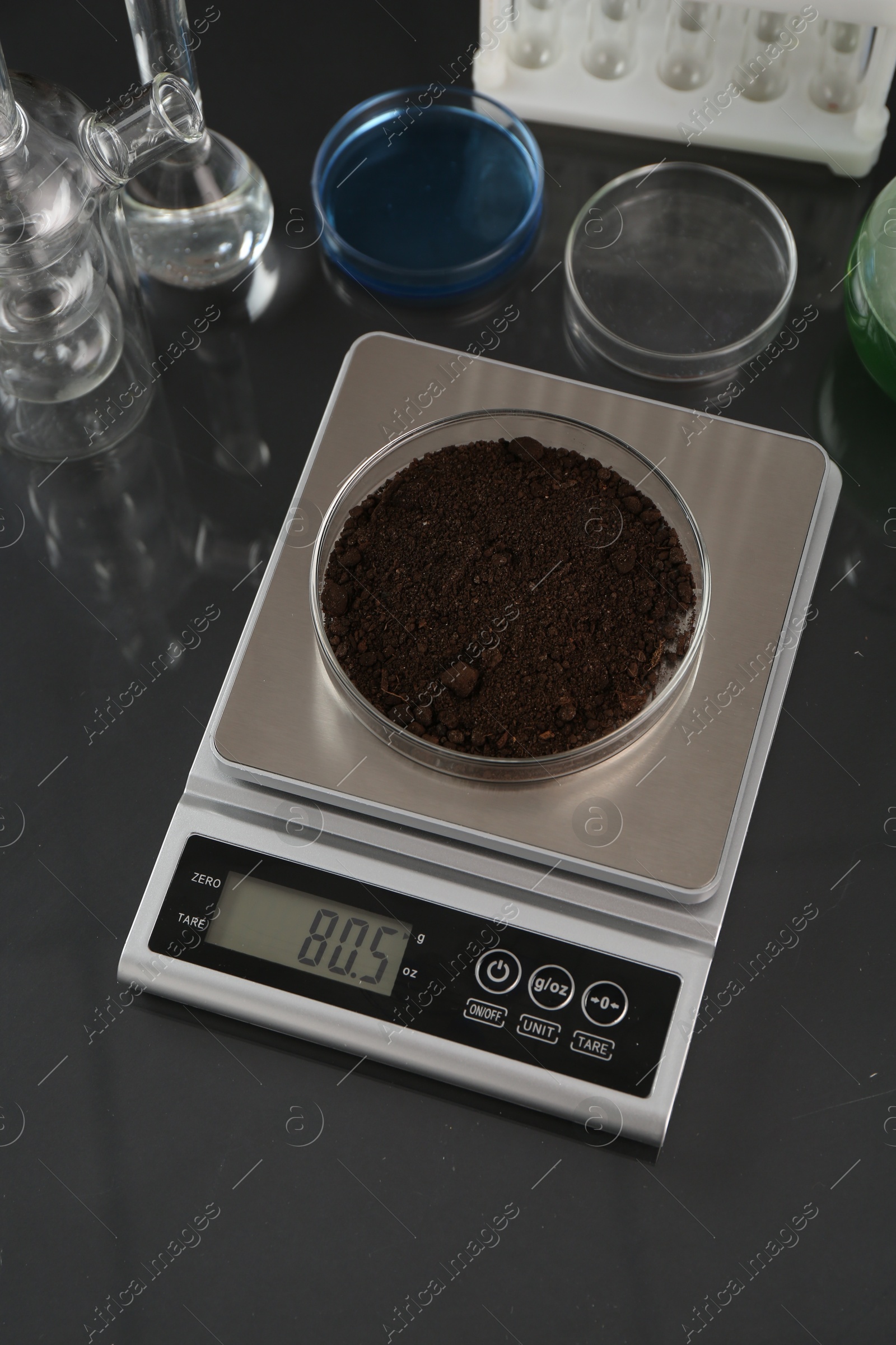 Scale with Petri dish of sample and other laboratory glassware on black mirror table, above view Photo of Scale with Petri dish of sample and other laboratory glassware on black mirror table, above view