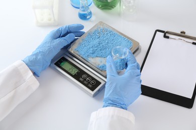 Photo of Scientist weighing sample on scales at white table, closeup