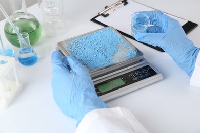 Photo of Scientist weighing sample on scales at white table, closeup
