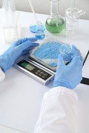 Photo of Scientist weighing sample on scales at white table, closeup