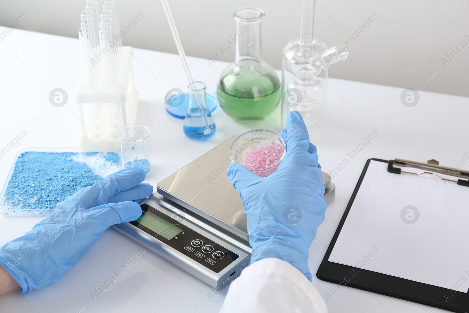 Scientist weighing sample on scales at white table, closeup Photo of Scientist weighing sample on scales at white table, closeup