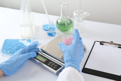 Photo of Scientist weighing sample on scales at white table, closeup